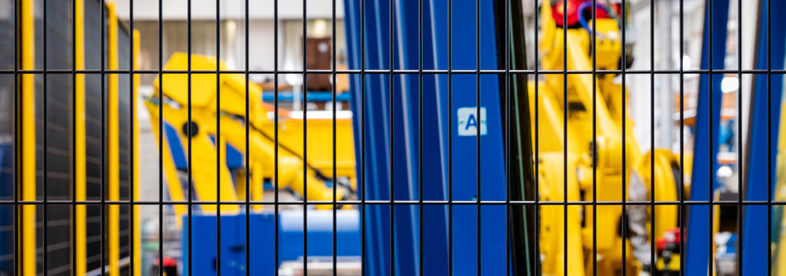 Dettaglio della rete di una protezione perimetrale Satech che recinta un macchinario industriale blu