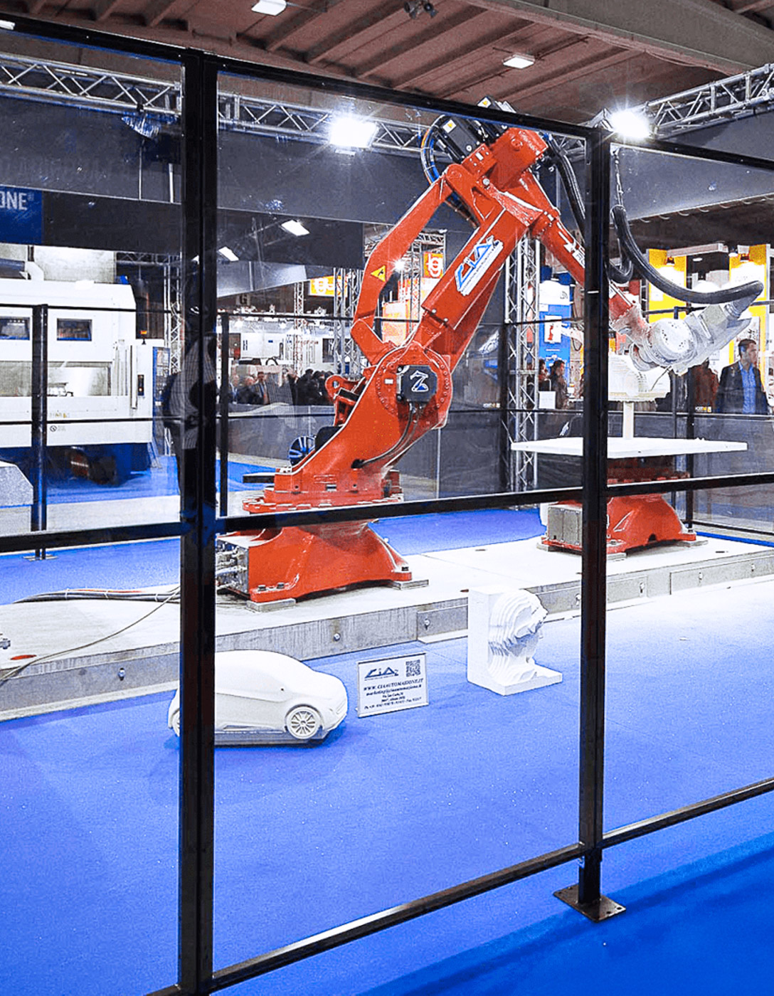 Satech polycarbonate panel protects red industrial robot at trade fair.