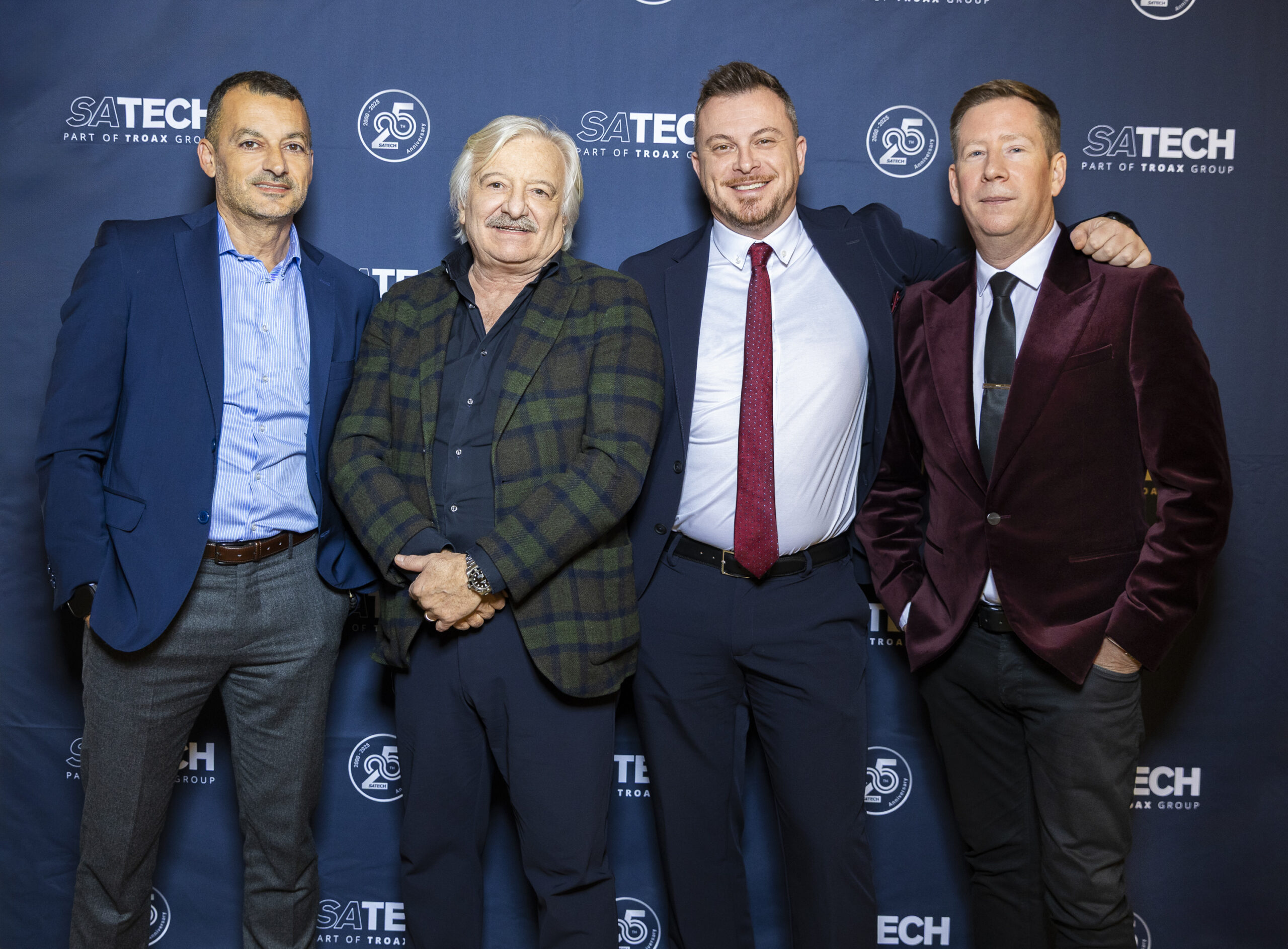 Gruppo del management di Satech in posa davanti al backdrop brandizzato durante una cena aziendale.
