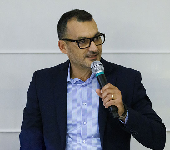 Satech CEO speaking into a microphone during a company dinner.