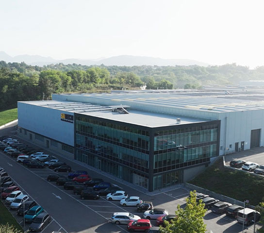 Veduta dall’alto della sede Satech di Bulciago, con stabilimento industriale, uffici vetrati e parcheggio esterno.