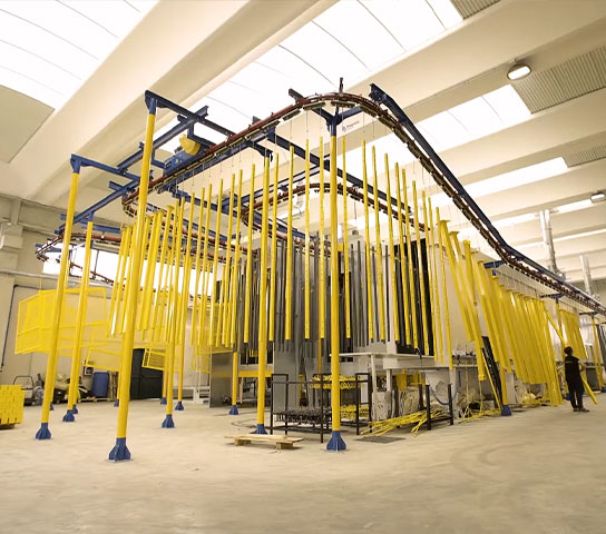 Automated industrial line for metal surface treatment, with overhead conveyor and components suspended during the production process.