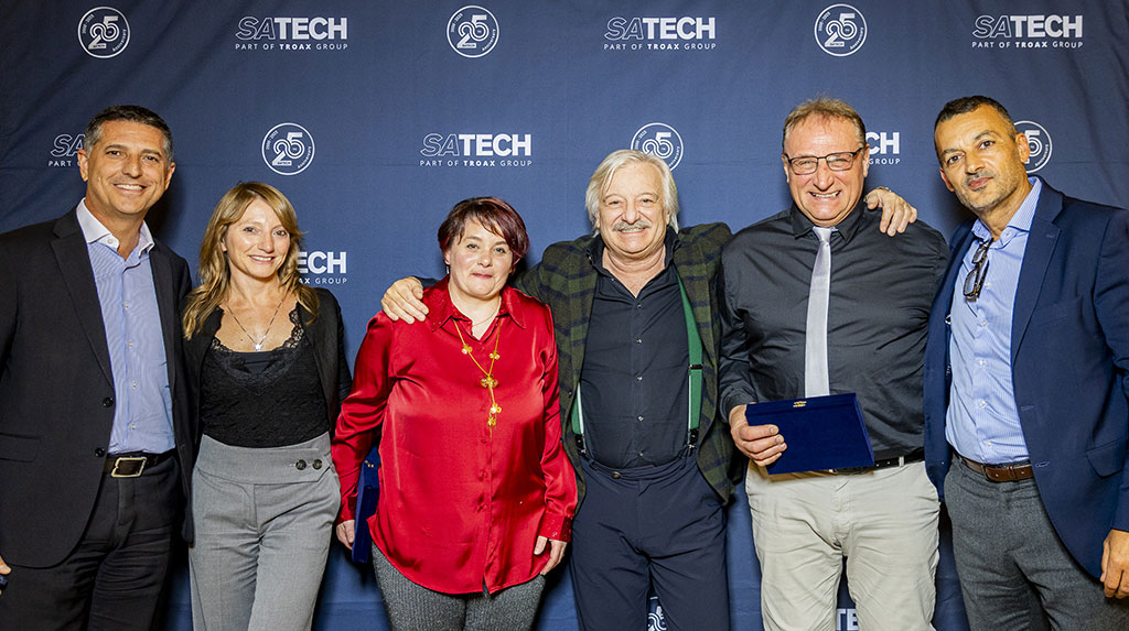 Gruppo del management di Satech in posa davanti al backdrop brandizzato durante una cena aziendale.
